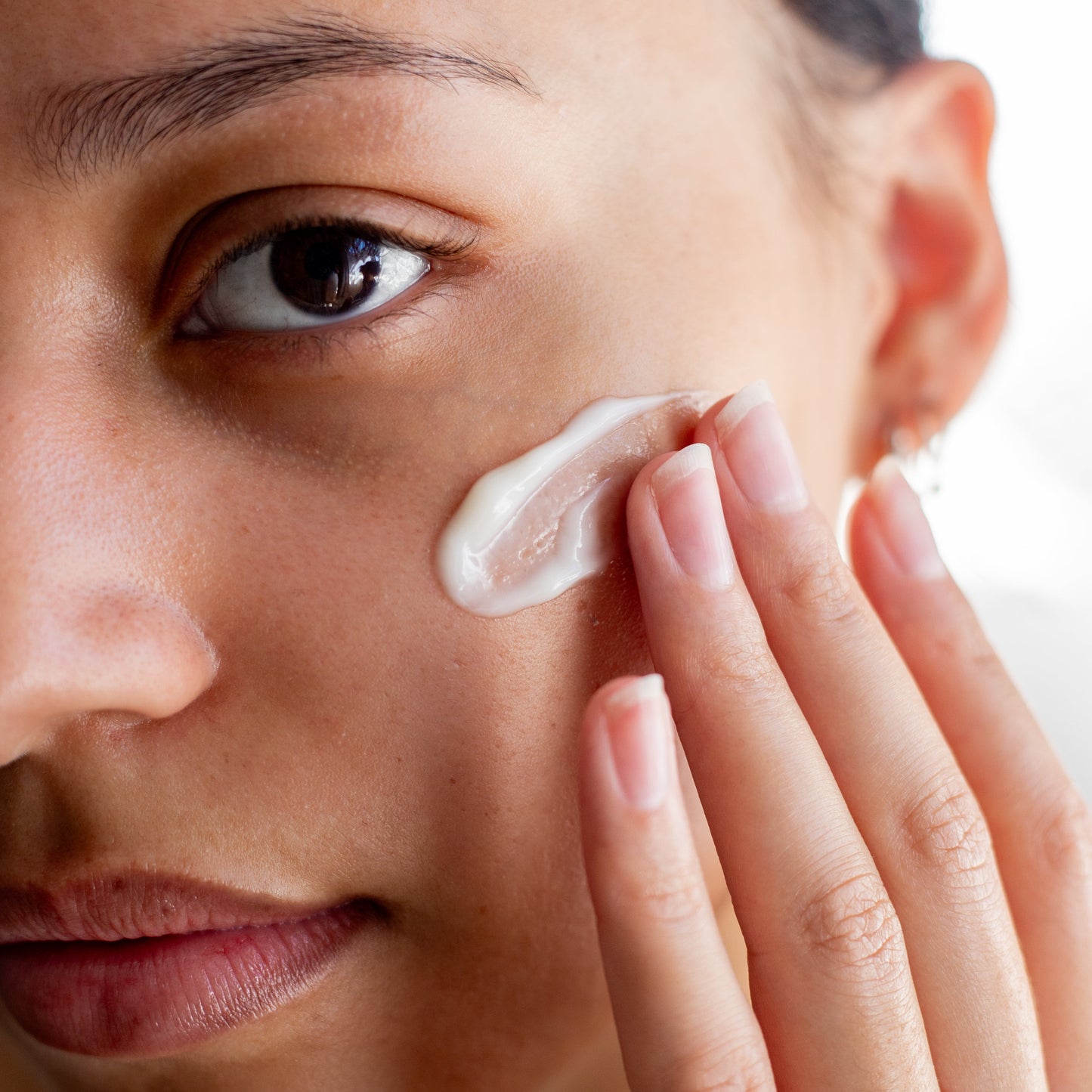 Woman applying cream to her face with a blurred background
