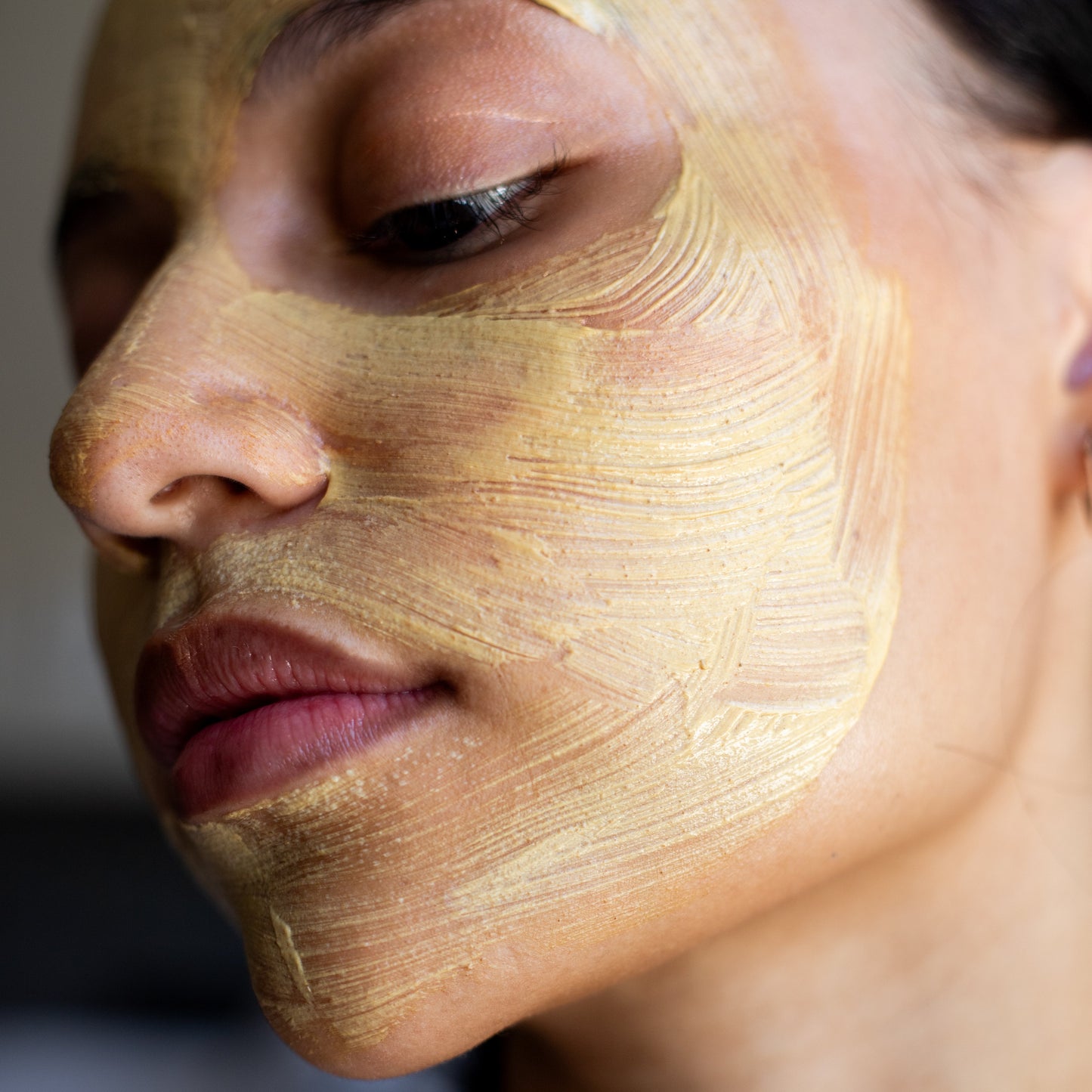 Close-up of a person with a gold face mask on, eyes closed.