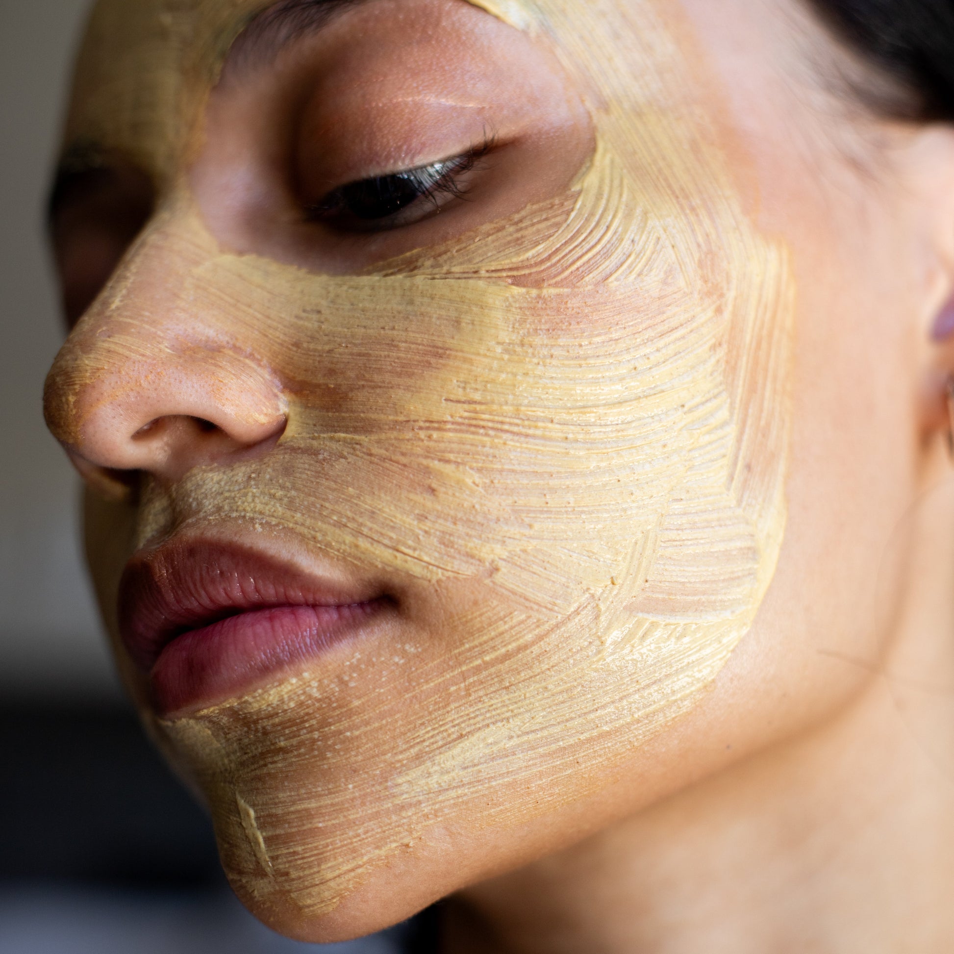 Close-up of a person with a gold face mask on, eyes closed.