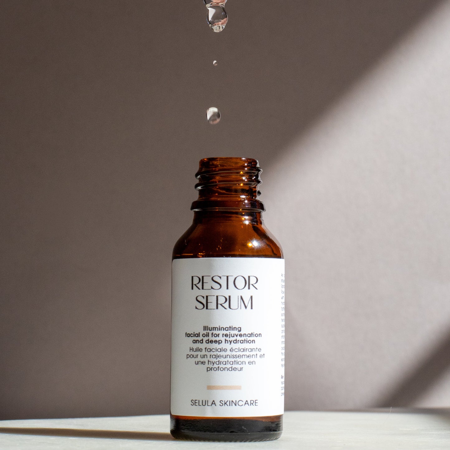 Brown serum bottle labeled 'RESTOR SERUM' with a dropper and droplet on a neutral background